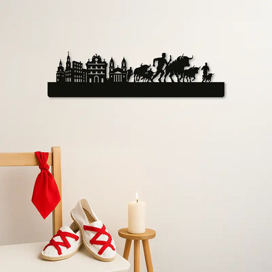 Skyline decorativo de un encierro de los Sanfermines en Pamplona colocado en una pared sobre silla con alpargatas, pañuelico y vela