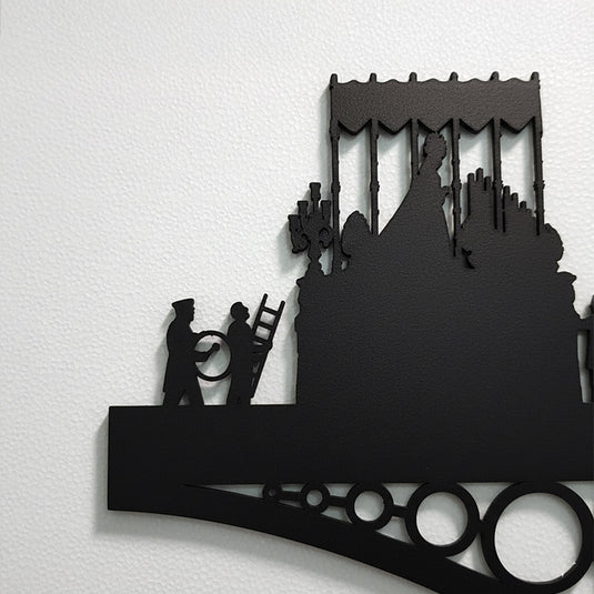 Detalle ampliado de silueta de madera representando la Virgen de la Esperanza sobre el Puente de Triana en Sevilla, decorando una pared blanca.