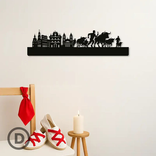 Skyline decorativo de un encierro de los Sanfermines en Pamplona colocado en una pared sobre silla con alpargatas, pañuelico y vela